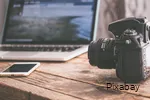 View of a table with laptop, smartphone and SLR camera.